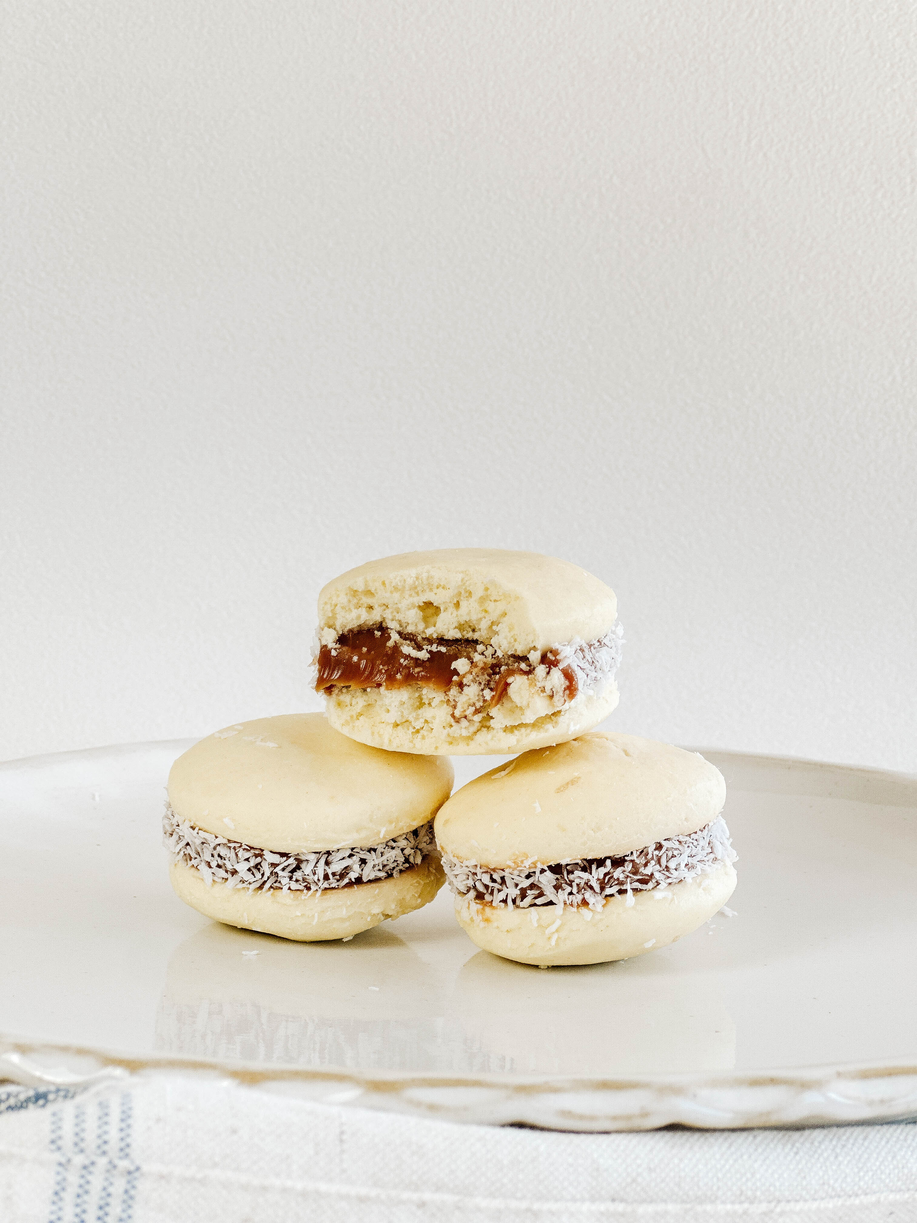 three traditional alfajores filled with dulce de leche and rolled in coconut flakes