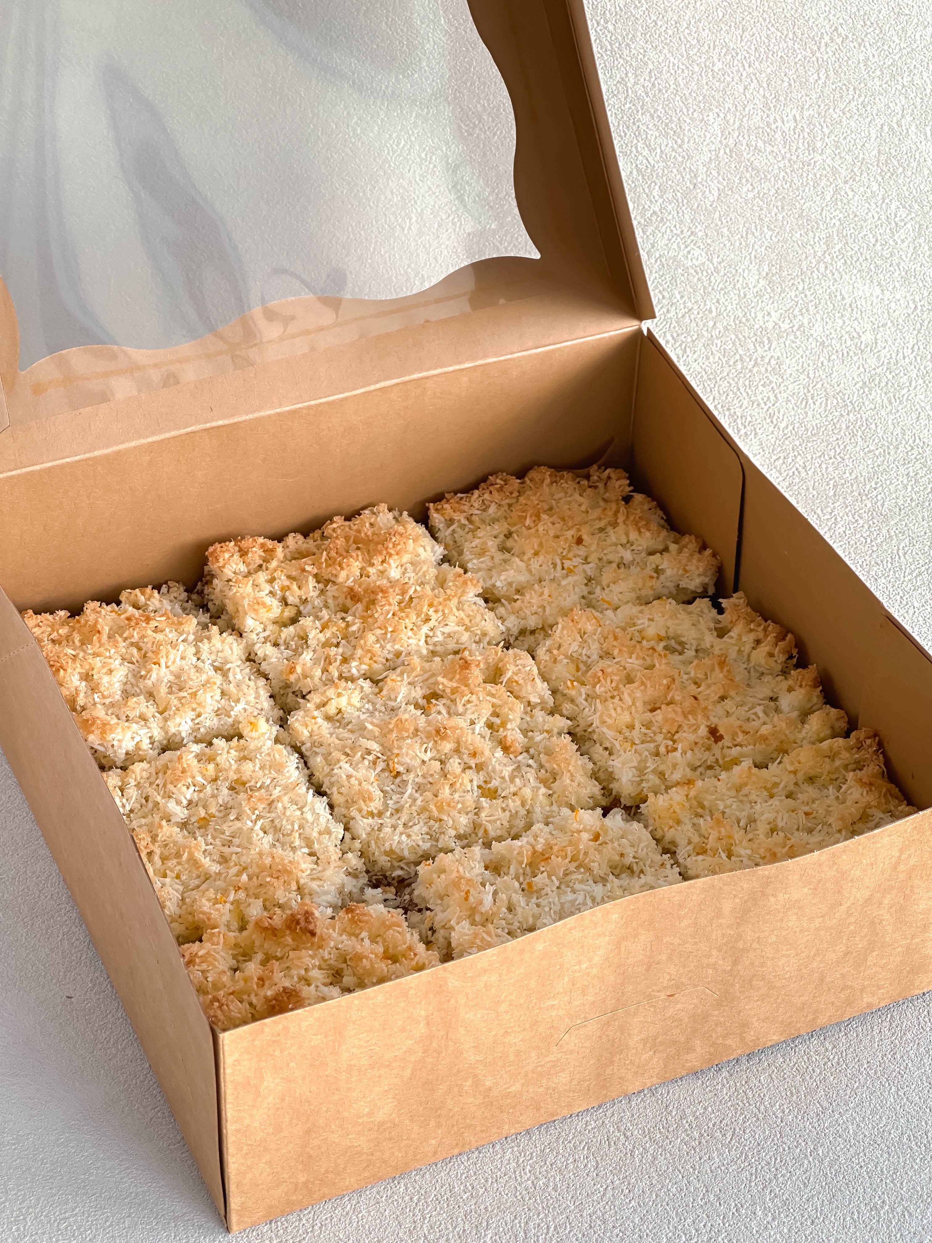 Box of coconut dulce de leche dessert bars on a light gray background.
