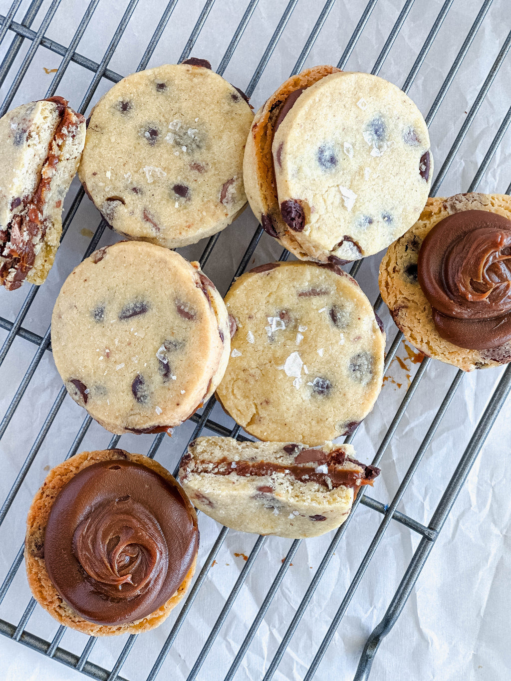Alfajor cookie sandwiches with dulce de leche filling on a cooling rack