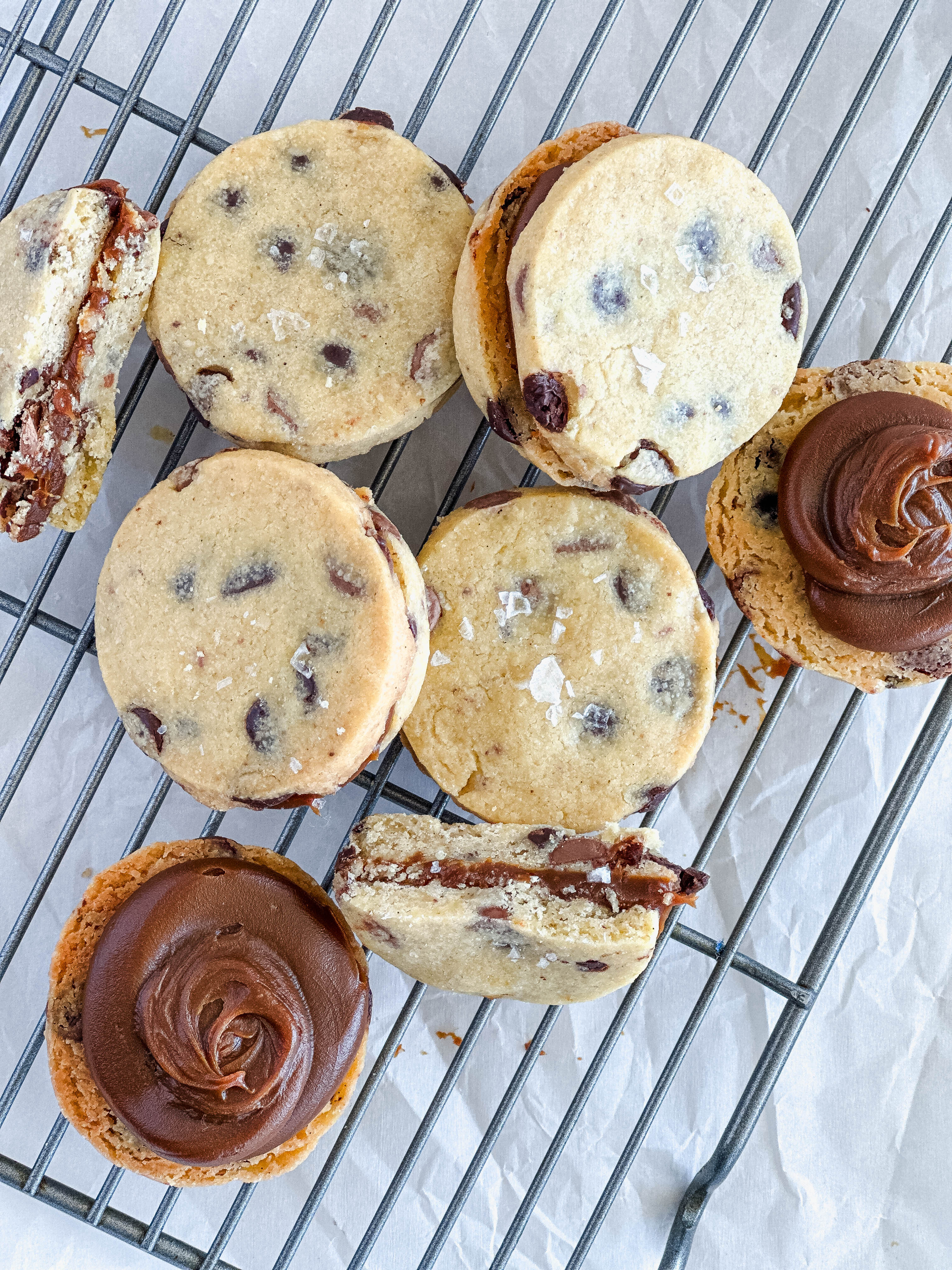 Alfajor cookie sandwiches with dulce de leche filling on a cooling rack