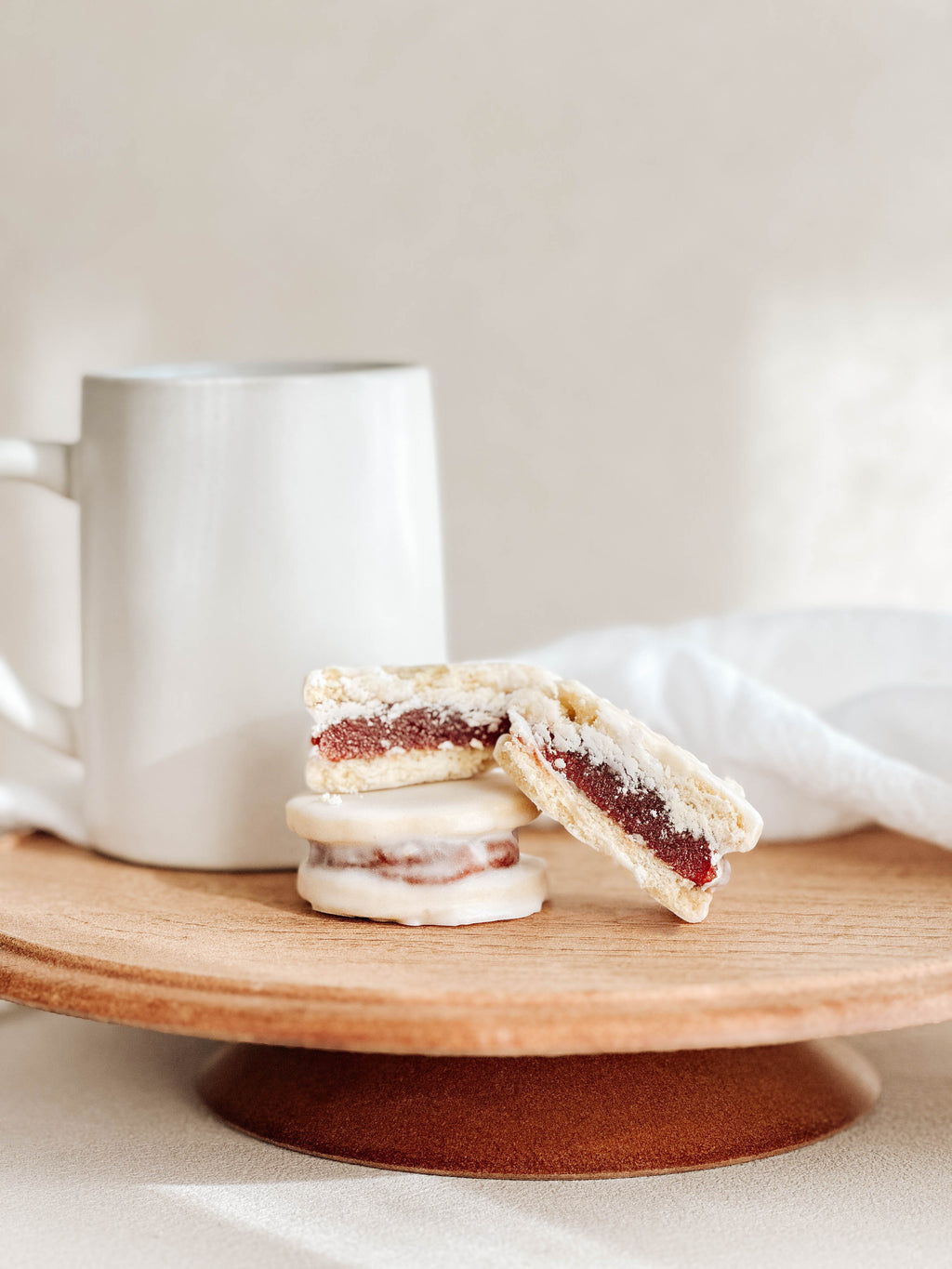 Guava alfajores cut in half showing guava filling on a wooden stand