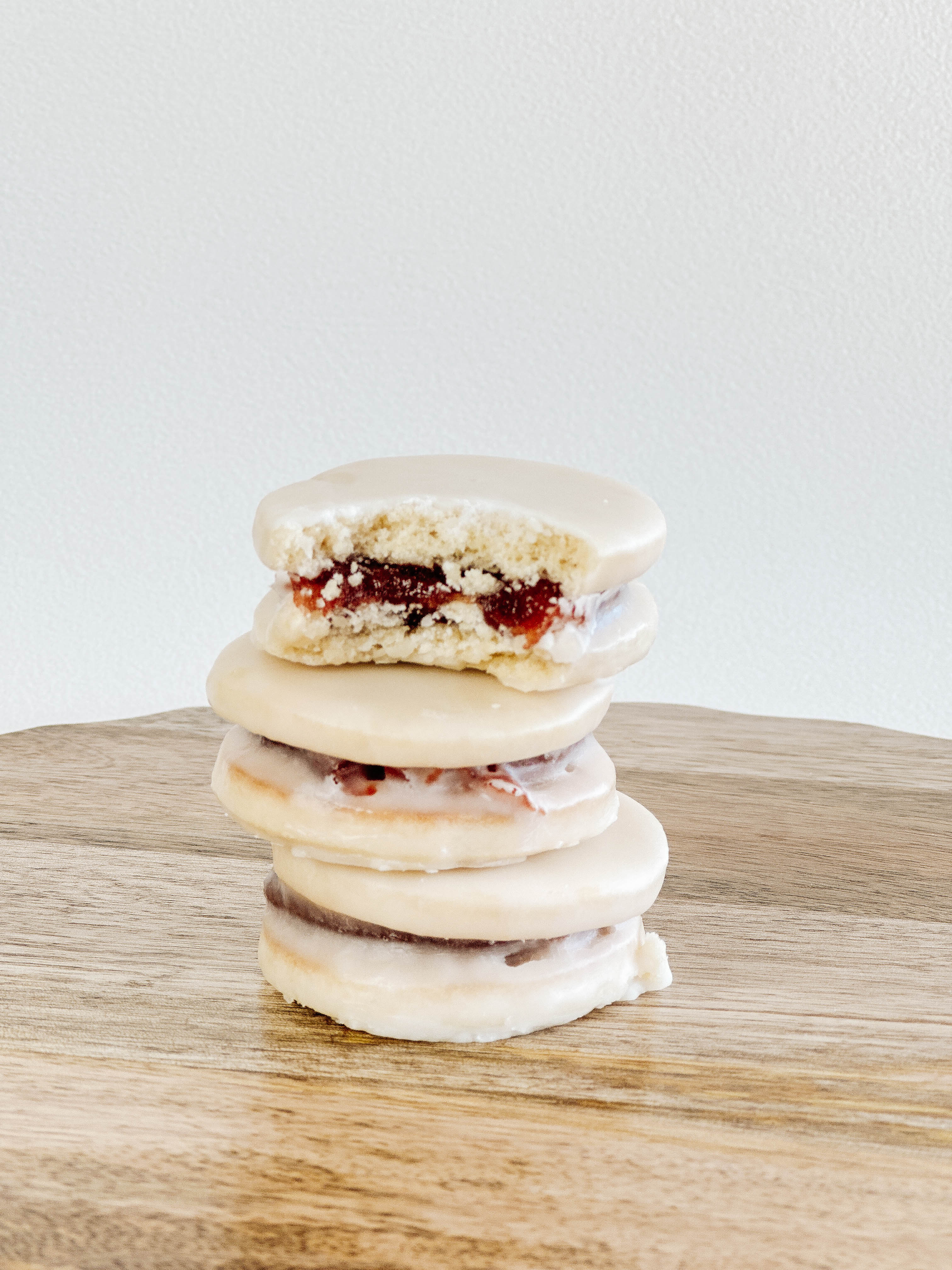 Stack of three guava alfajores cookies on a wooden surface with a light background