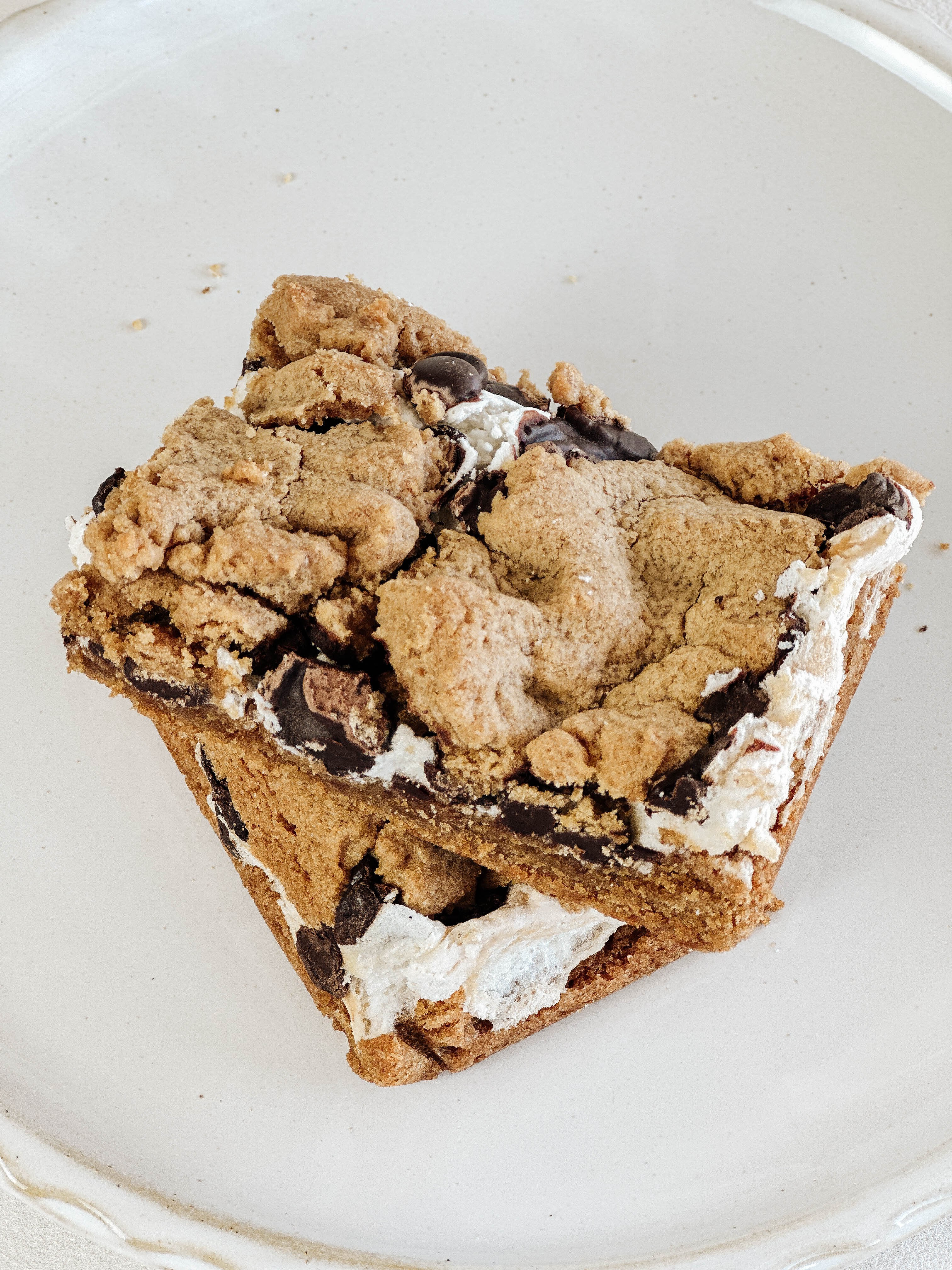 Cookie bar with homemade marshmallow and belgian dark chocolate chips on a white plate.