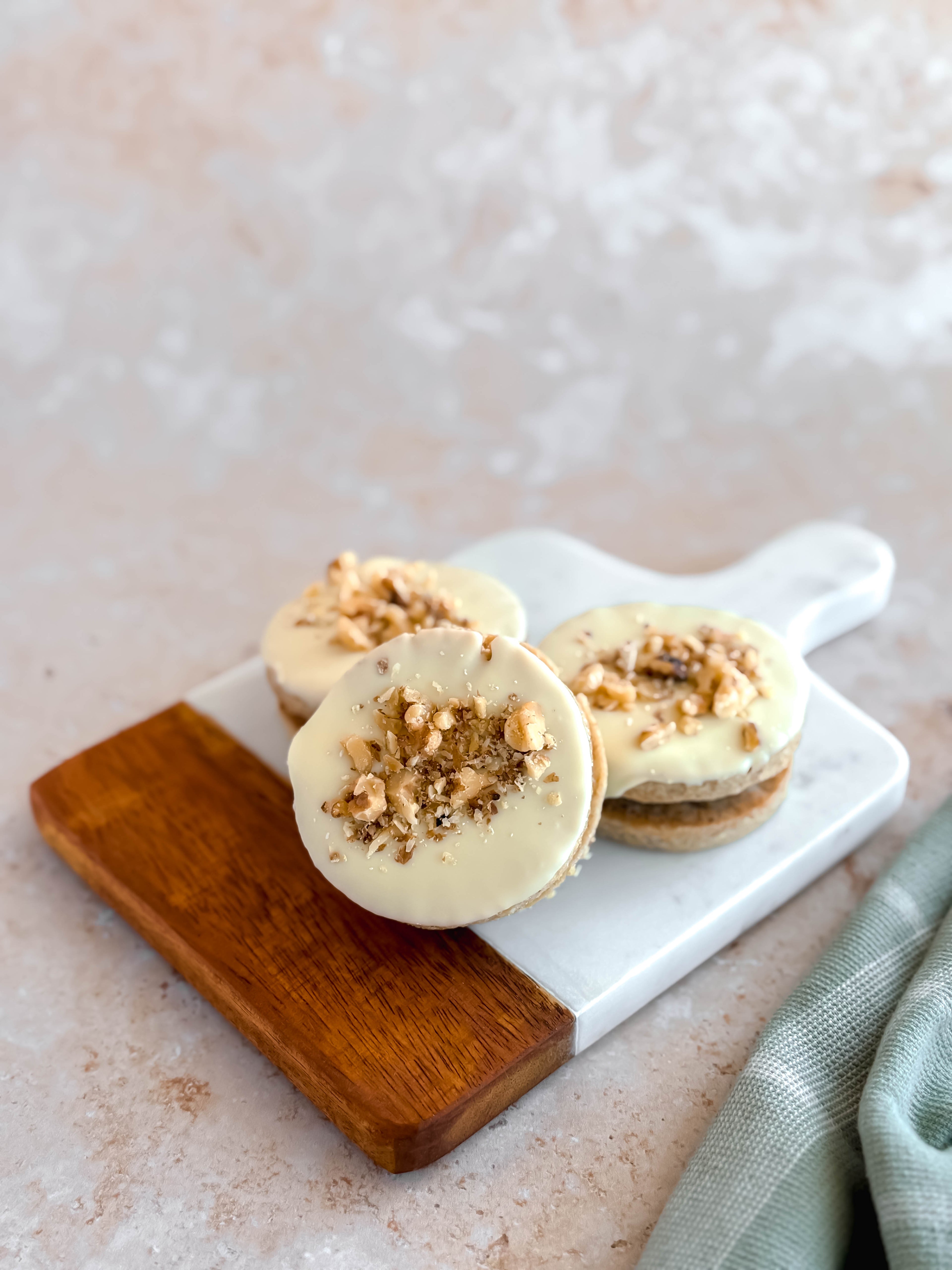 three walnut alfajores filled with dulce de leche and topped with belgian white chocolate